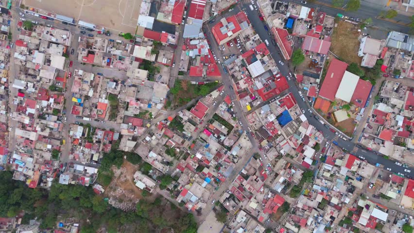 Cenital drone shot of Huixquilucan showcases densely packed homes, highlighting urban poverty, social displacement, and economic disparity in Mexico’s evolving urban landscape. Camera gently descends