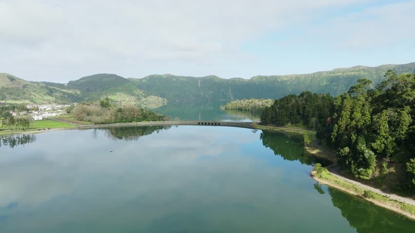 Aerial pullback view over Sete Cidades calm green lake mirroring reflections