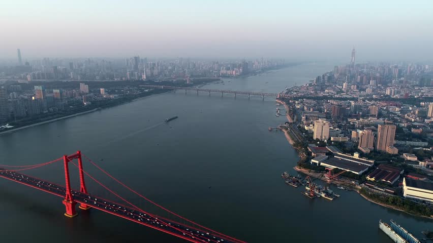 An aerial view of the Yangtze River in Wuhan, showcasing the expansive river surface with various docks and ships of different sizes scattered along the bustling waterfront
