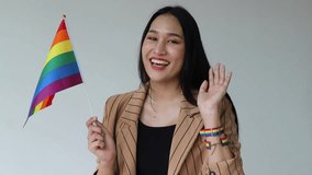 Happy smiling non-binary LGBT person saying hi, waiving welcoming hand, showing rainbow flag for LGBT awareness pride month - Powered by Shutterstock - Get 15% off with code: PIKWIZARD15