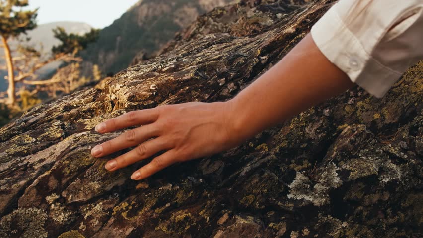 woman hand touching stone rock. hand close up. texture of ancient rocks mountains nature. traveler girl climbing rocks at sunset summer. panoramic view city capital Andorra la Vella. moss-grown stone