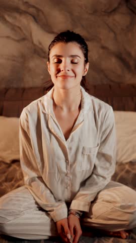 Practicing mindfulness and relaxation techniques in cozy bedroom setting at home in the evening
