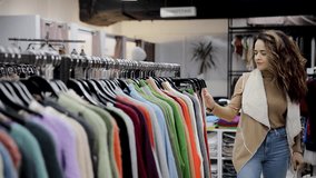 Woman choosing warm sweater hanging on hangers on clothing racks in clothing store. Collection of winter clothes. Buying warm clothes concept - Powered by Shutterstock - Get 15% off with code: PIKWIZARD15