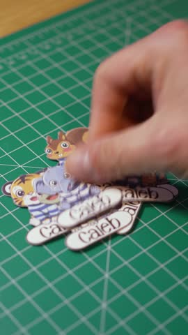 Vertical view of a crafter placing a child's name labels on a cutting board.  	