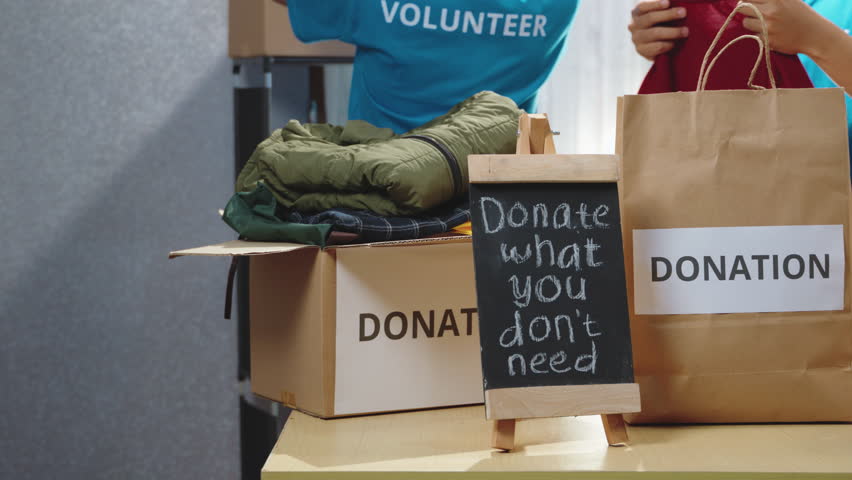 Donation boxes and essential food items displayed on a desk in a charity center. Volunteers preparing additional supplies for those in need. Humanitarian aid, food donations, charity work