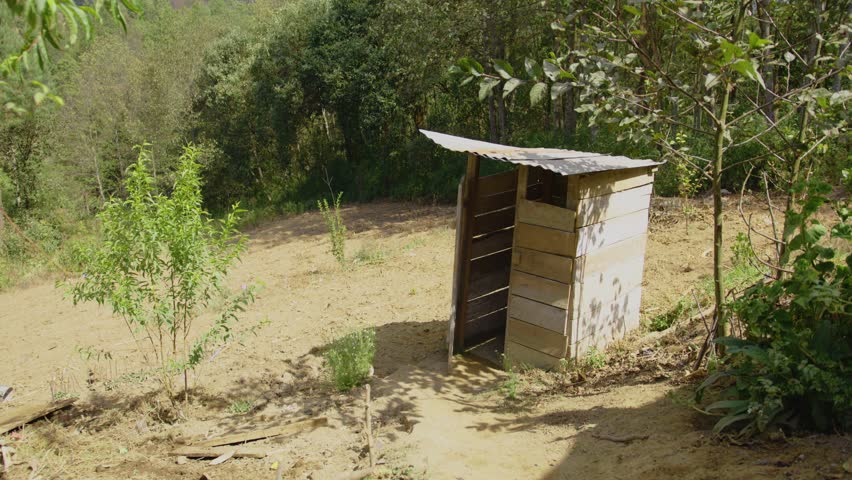 This striking image captures a rustic latrine in the middle of a crop field, symbolizing rural poverty and basic sanitation challenges. The humble structure reflects limited resources and the need