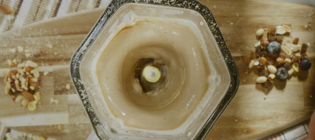 Super slow-motion shot of an unrecognizable man blending protein powder with milkshake in the blender