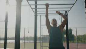 An athletic man intently performs a pull-up on monkey bars in an outdoor fitness park. The sun glows softly in the background, creating a vibrant and motivational atmosphere. Focused Athlete - Powered by Shutterstock - Get 15% off with code: PIKWIZARD15