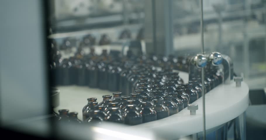 Conveyor in the Laboratory at the Pharmaceutical Enterprise with Glass Brown Bottles. Transfer to injection packaging line. Pharmacy factory. Healthcare and automated technology concept.
