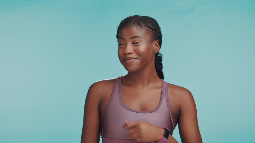 Black woman, fitness and face in studio with pointing, sports announcement or happy with space. Personal trainer, excited or showing gesture on blue background for gym sign up promotion or membership