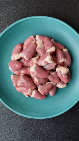Raw chicken hearts with salt, spices and herbs on a dark concrete background