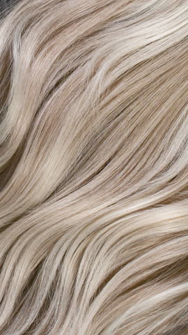 Vertical blond hair texture, slow motion of female hand combing long curly hair