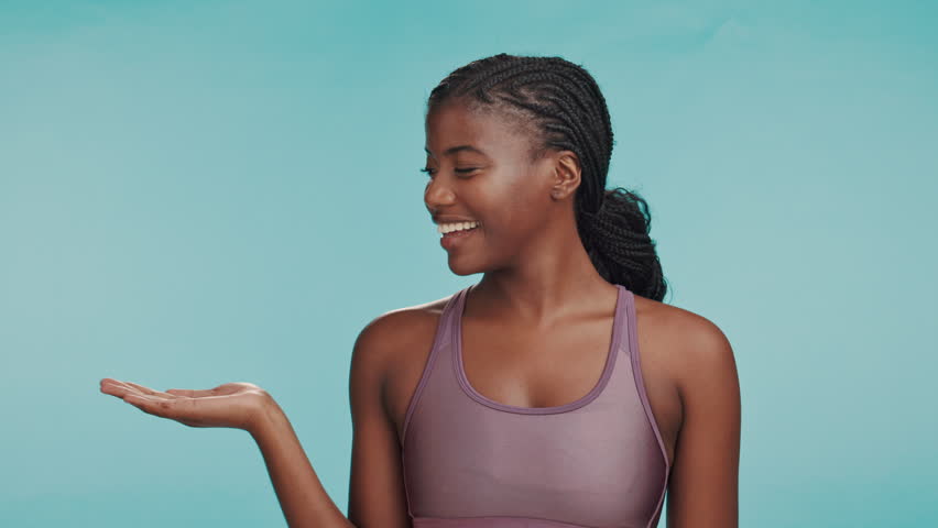 Happy woman, fitness and face with product placement for announcement, offer and promo in studio. Personal trainer, excited and show gesture on blue background space for gym advertising or membership