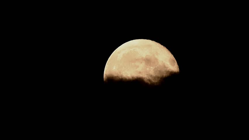 Full moon rises through drifting clouds in cinematic time lapse showcasing the night sky