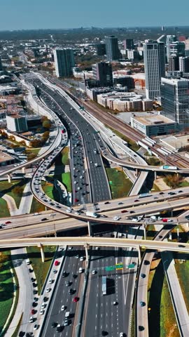 This aerial view captures the bustling highways and modern architecture of Dallas, Texas, showcasing the vibrant urban landscape under clear blue skies.