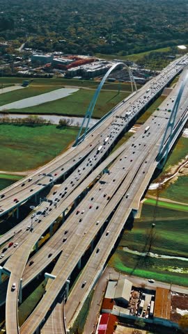 A breathtaking aerial perspective of Dallas reveals busy highways weaving through lush green parks and urban terrains. The dynamic city skyline frames the horizon.