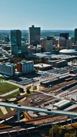 Skyline of Dallas reveals a mix of modern architecture, bustling highways, and green spaces under clear skies. The urban center thrives with activity and energy.