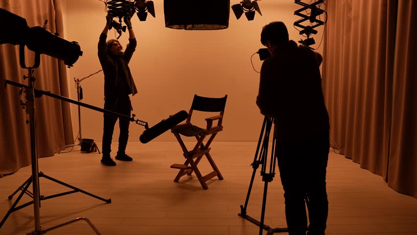 Studio for photo video production filming with lighting equipment and cyclorama, team members taking off lights and camera, director chair stands in the middle.