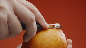 Getting orange peel with a special kitchen tool, orange juice with essential oils sprinkling out under the cut on orange background. Slow motion macro video.  - Powered by Shutterstock - Get 15% off with code: PIKWIZARD15
