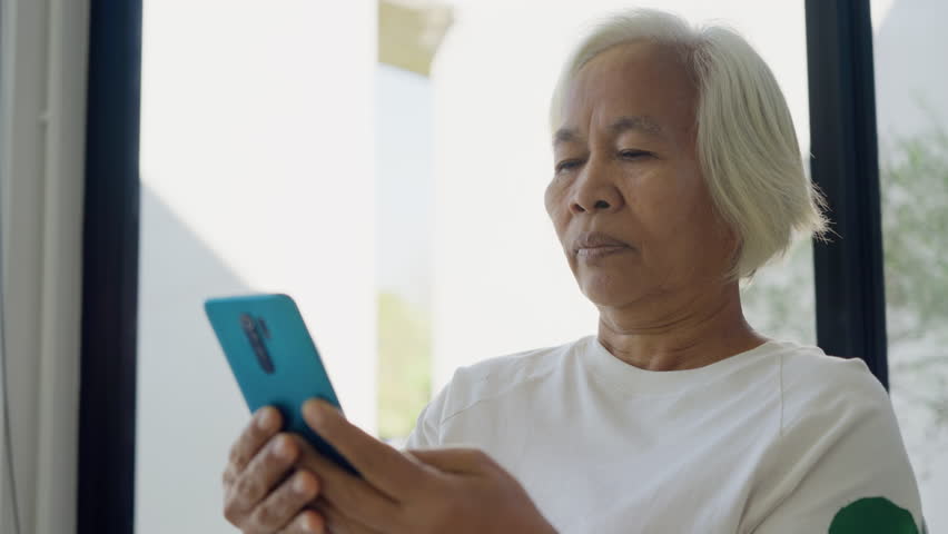 Phone scam call target talk old asian female cyber crime fraud alert on older people. Mature adult retired woman asia parent avoid look at text threats mobile buy pay online banking app social media.