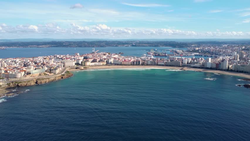 Bautiful panoramic aerial perspective of A Coruna city. Drone going backwards above the bay. Old historic center of the city and Port of A Coruna. Orzan Beach. Fanous travel destination in Galicia.