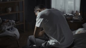 Sadness and regret overwhelm young man sitting on edge of unmade bed. African American man holds head in hands suggesting state of emotional distress - Powered by Shutterstock - Get 15% off with code: PIKWIZARD15