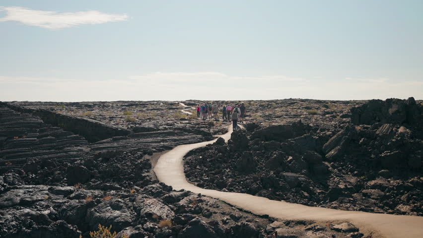Visitors hike along a scenic path in Craters of the Moon National Park, taking in the unique volcanic landscapes and rugged terrain of this awe-inspiring location.