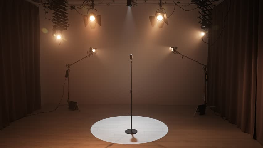 Studio for photo video production filming with lighting equipment and cyclorama, retro vintage microphone stand standing in the middle under bright spotlight.