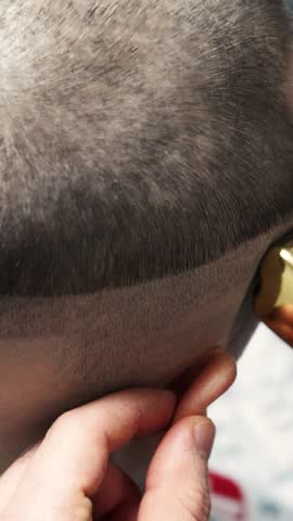 young guy cuts his hair and makes a short bald haircut. Master barber in a barbershop makes a haircut to a client close-up. Skinhead man of criminal appearance shaves his head with a machine