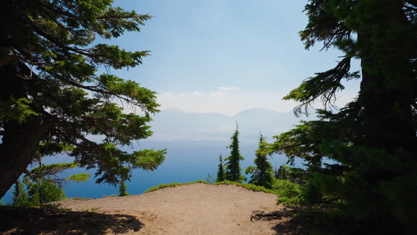 A breathtaking view of Crater Lake emerges from the surrounding woodland, revealing its deep blue waters framed by lush green trees.