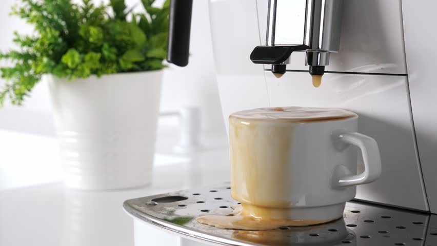 White coffee machine making espresso. Americano dropping in white cup and overflow. Preparation process. Nobody