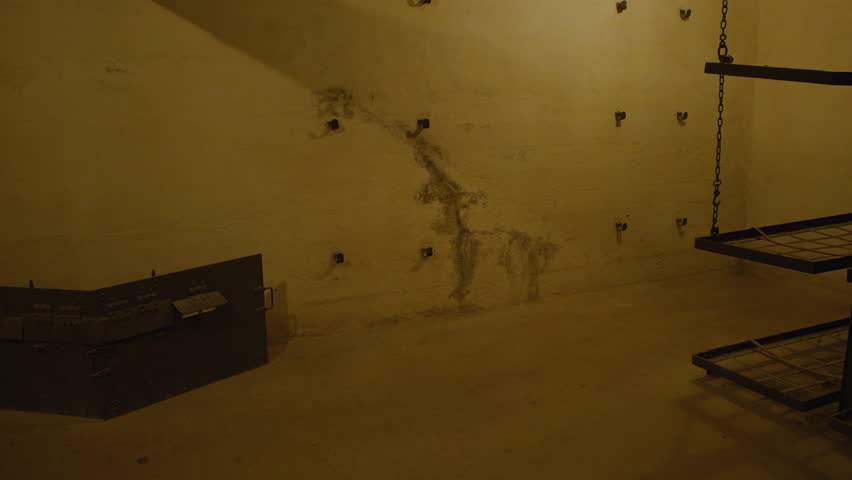 Old bunk beds in dimly lit bunk room with aged weathered walls. Bunk room in Fort de Mutzig fortress