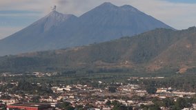 Aerial view of Acatenango volcano with Volcan de Fuego erupting ash plume with Antigua in foreground, telephoto daytime drone shot - Powered by Shutterstock - Get 15% off with code: PIKWIZARD15