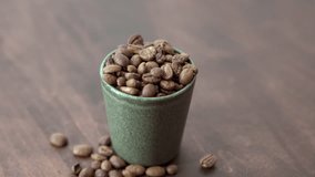 This close-up shot captures an overflowing small cup filled with coffee beans, resting on a wooden table. creating a delightful contrast against the rustic wood grain, evoking the essence of coffee. - Powered by Shutterstock - Get 15% off with code: PIKWIZARD15