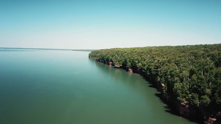 A drone captures a stunning aerial view of Apostle Islands, featuring lush greenery and calm waters of Lake Superior.