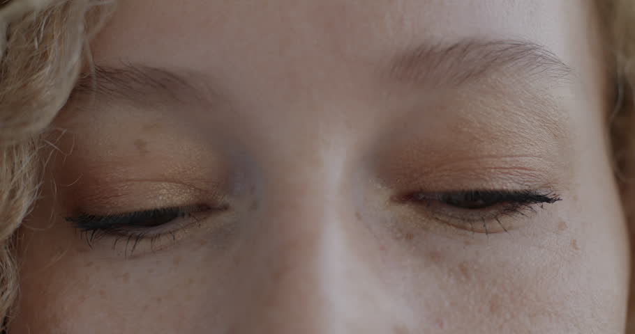 Close-up of female eyes looking at camera blinking while calm lady expressing no emotion. Human body part and face expression concept.