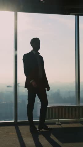 Young Adult Caucasian Entrepreneur Looking into Window Generating New Successful Business Ideas Contemplating Future Staying in Modern Office.