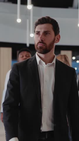 Young bearded confident businessman walking into office through business center corridor. Diverse people. Business community. Colleagues.