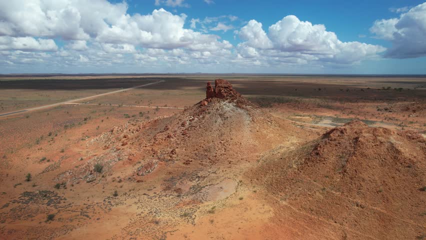 Aerial view of barren desert landscape with rugged rock formations and vast terrain under a sunny sky, Great Northern Highway, Turtle Head, Pilbara Region, Australia.