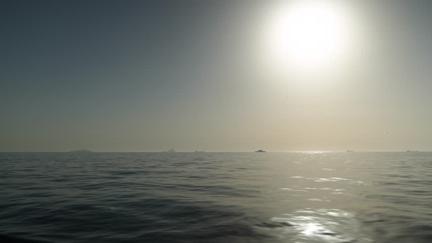 Sunrise over the foggy sea with the view of faraway ships.