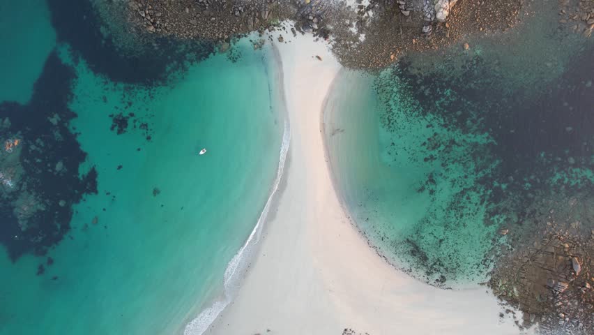 Aerial view of the beautiful Plage des Amiets beach with serene waves and a tranquil ocean at sunrise, Cleder, France.
