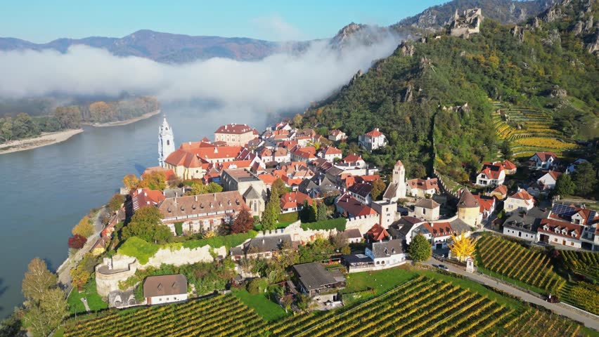 Aerial view of picturesque medieval town with vineyards and fortress by the Danube River in autumn, Durnstein, Austria.