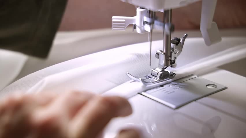 seamstress makes an even stitch on the sewing machine. seamstress's experience allows her to do this quickly and efficiently. The seamstress's hands hold fabric precisely to achieve the best result.