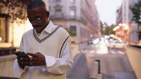 Smiling Black man scrolls through social media on mobile phone, engaged in reading online content. Male technology user focused with modern digital habits while reading online information with 5G - Powered by Shutterstock - Get 15% off with code: PIKWIZARD15