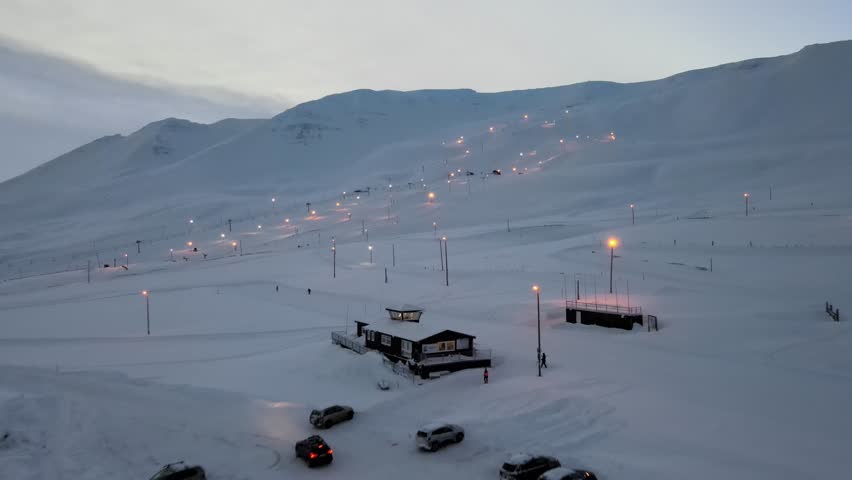 Aerial view of snowy alpine landscape with ski resort and mountain peaks, Akureyri, Iceland.