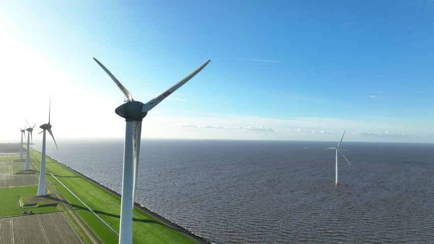 Wind turbines on a lakeshore and off shore wind turbines producing sustainable energy during a sunny day