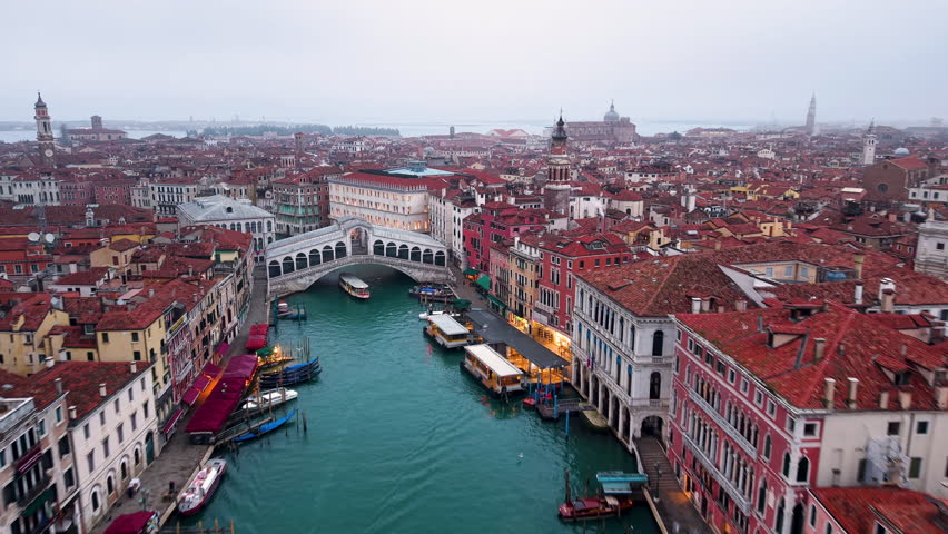 Aerial view of Venice, Italy featuring the famous Rialto Bridge and gondolas traveling through the Grand Canal