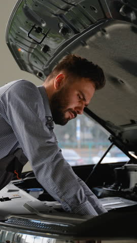 Focused mechanic repairing car engine in modern service center