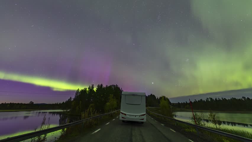 Camper van driving under a beautiful aurora borealis timelapse at night near Kiruna, Sweden
