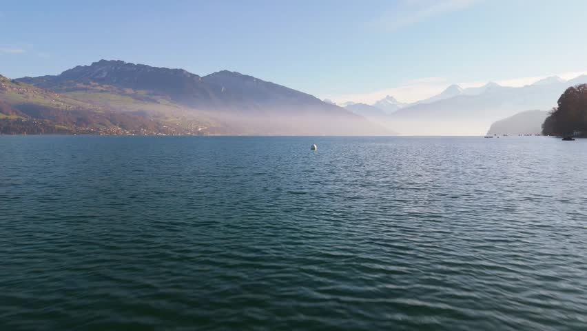 Close Droneflight over the lake Thun with the mountainscape in the background.